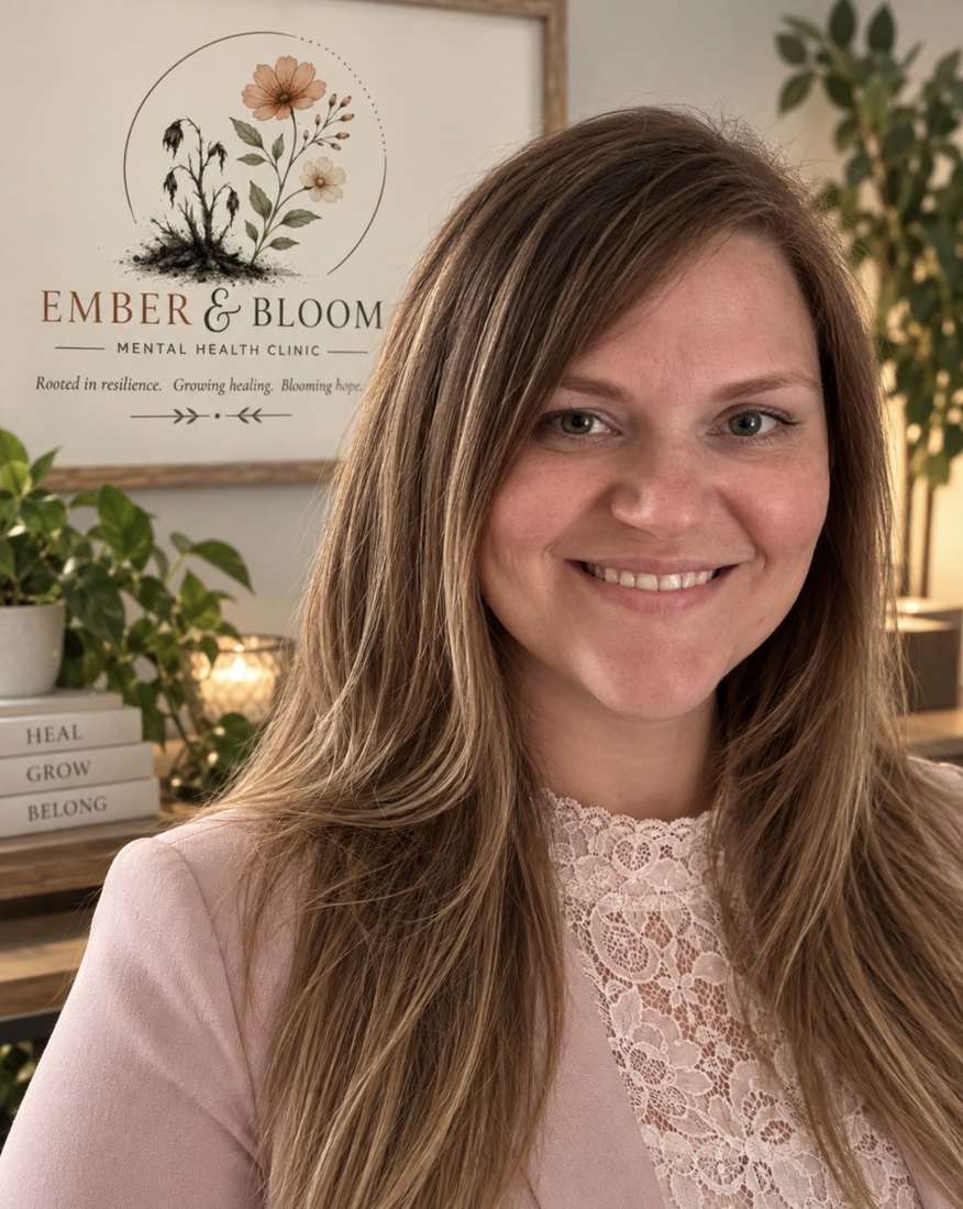 Kathy Spears, APRN, PMHNP, seated in her office in front of the framed Ember and Bloom sign, with plants and warm lamplight behind her.